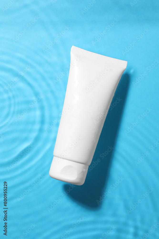 Tube with moisturizing cream in water on light blue background, top view Tube with moisturizing cream in water on light blue background, top view