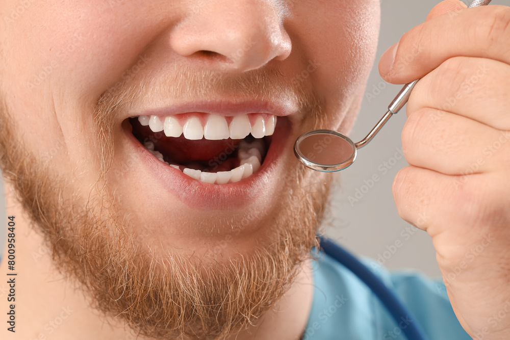 Obraz premium Male dentist with tool smiling on light background, closeup
