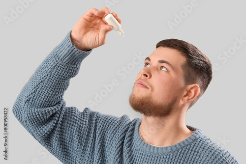 Young man putting eye drops...