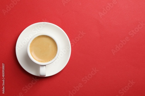 Aromatic coffee in cup on red background, top view. Space for text