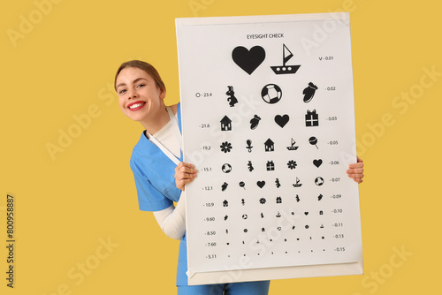 Female ophthalmologist with eye test chart on yellow background