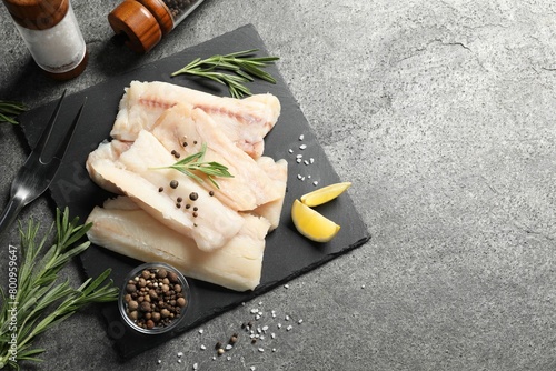 Canvas Print Pieces of raw cod fish, rosemary, peppercorns and lemon on grey table, top view
