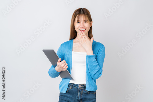Happy casual Asian girl student holding laptop with hands over mouth on white background.