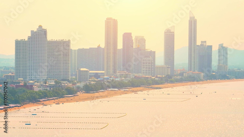 Serene Beauty: Jomtien Beach at sunset is a tranquil paradise, where golden hues paint the sky, and gentle waves whisper along the shore. Pattaya, Thailand. Aerial view drone. Tropical sea concept.  © Punyawee