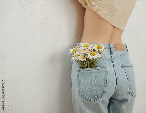 Backside view of young pretty woman. Chamomile flowers bouquet in jeans pocket