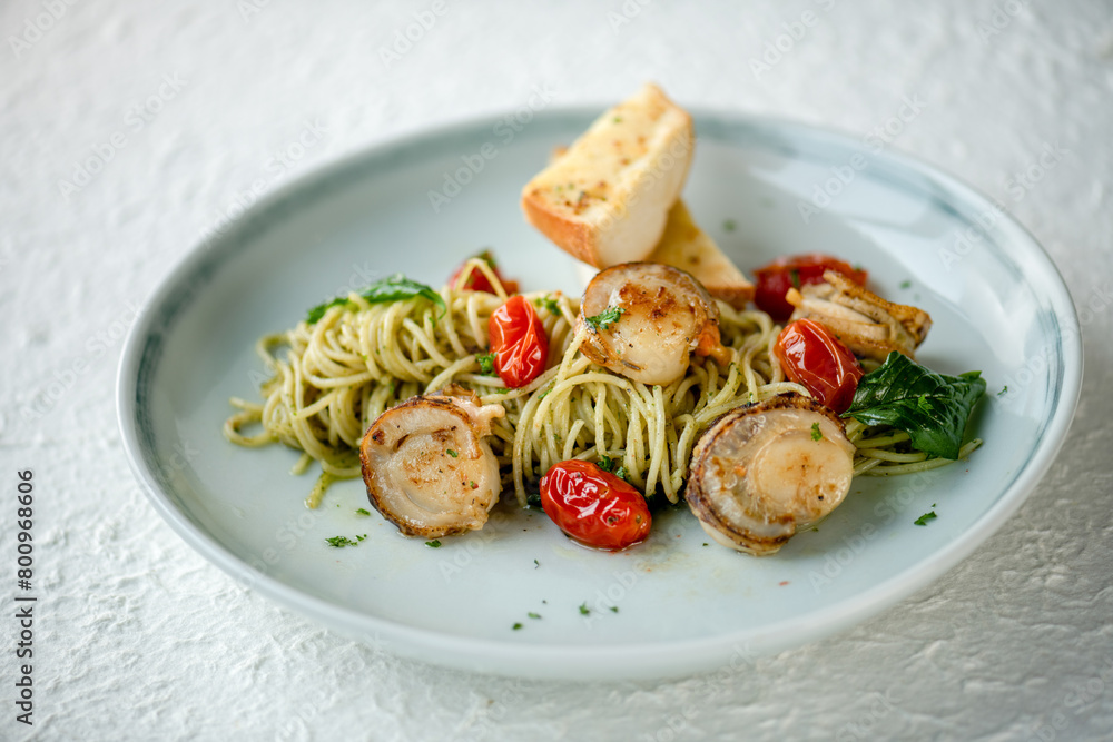 A plate of seafood pasta with cherry tomatoes and a side of garlic bread. A plate of seafood pasta with cherry tomatoes and a side of garlic bread.