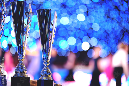 Close-up of golden trophies lined up at a dance event. Collection of trophies. Award cups closeup with space for text on neon background