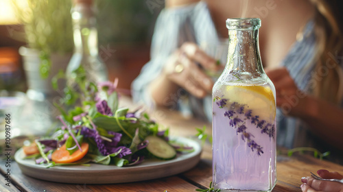 Glass bottle of lavender lemonade with woman eating 