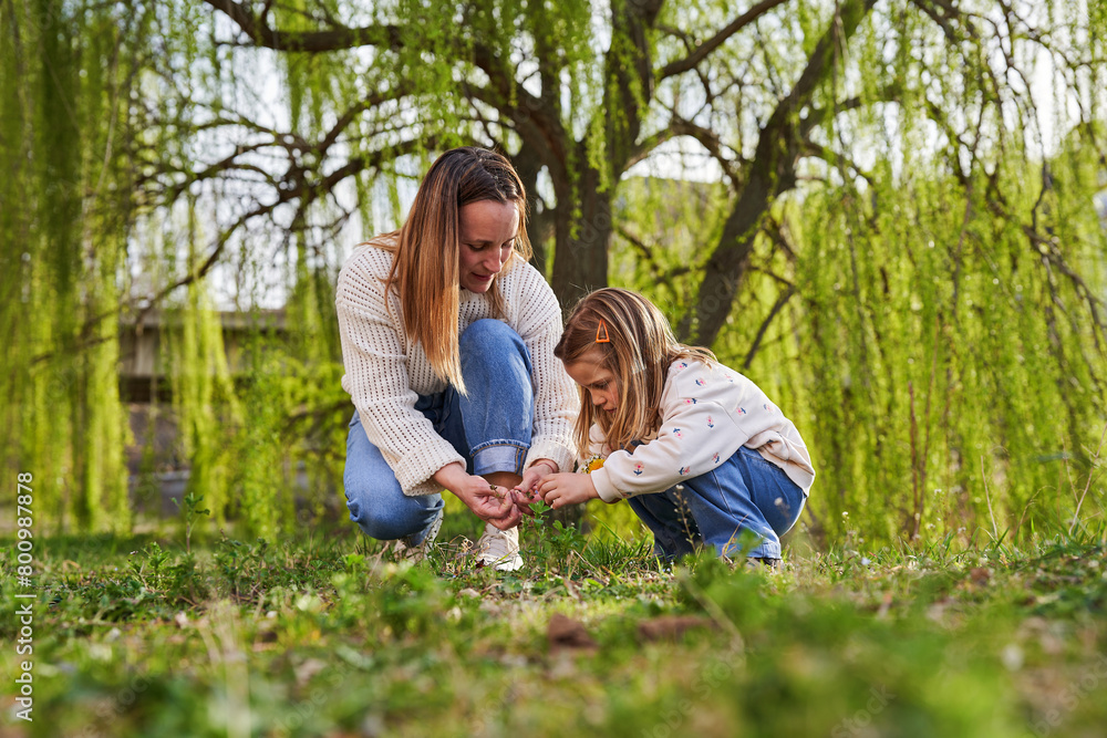 Mother and daughter playing in the grass in their weekend walk Mother and daughter playing in the grass in their weekend walk