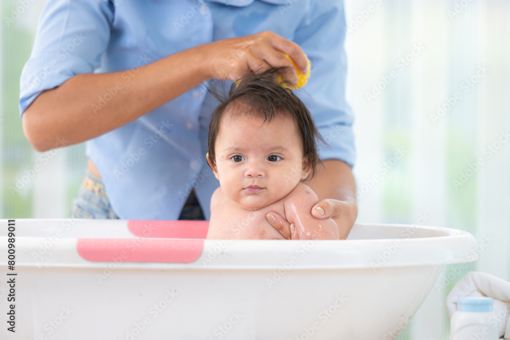 A mother bathes her little daughter in a small children's tub. A mother bathes her little daughter in a small children's tub.