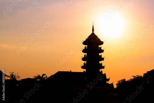 Black silhouette of Pagoda of Che Chin Khor Temple against orange dusk sky at Bangkok, Thailand. Chinese temple on the banks of the Chao Phraya river