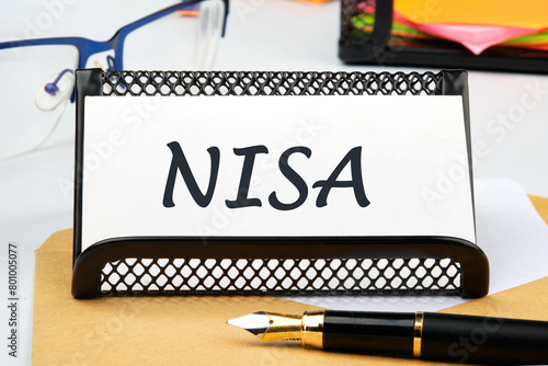 The word Nippon Individual Savings Account. NISA the inscription on the business card on the table near the pen, a calculator, a stand with a ticker photo