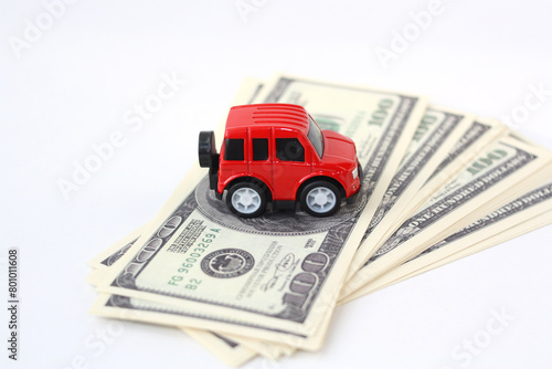 A red toy car sits on a stack of dollars.
Concept - buying a car, selling, paying off a loan, leasing, repairing. Cost concept for paying car bills.