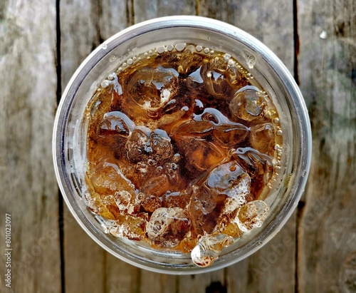 Cola soft drink with ice cubes on wood background