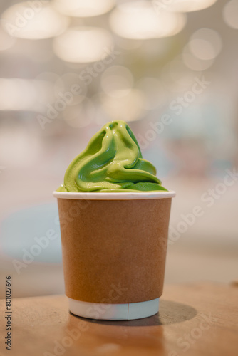 Matcha ice cream in a disposable paper cup with bokeh background