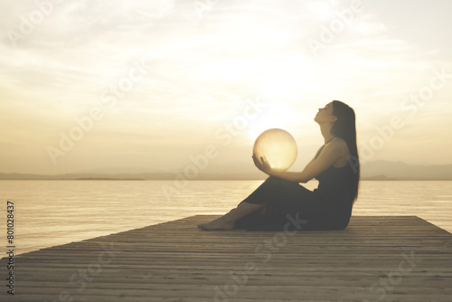 woman protecting a magical sphere illuminated by the sun that releases energy and inner strength, abstract concept