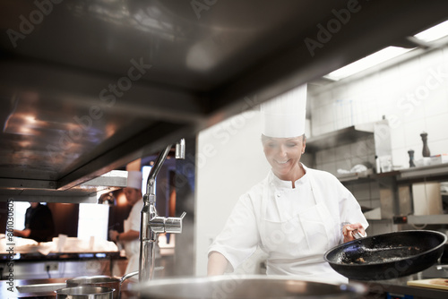 Cooking, chef and happy woman in kitchen at restaurant for fine dining, service and hospitality. Expert, culinary professional and worker with pan for meal prep, dinner or frying food for catering