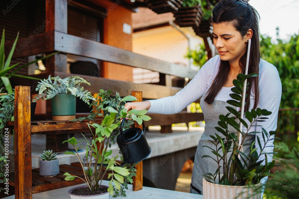 One young caucasian woman is taking care of her plants using plant mister and water can