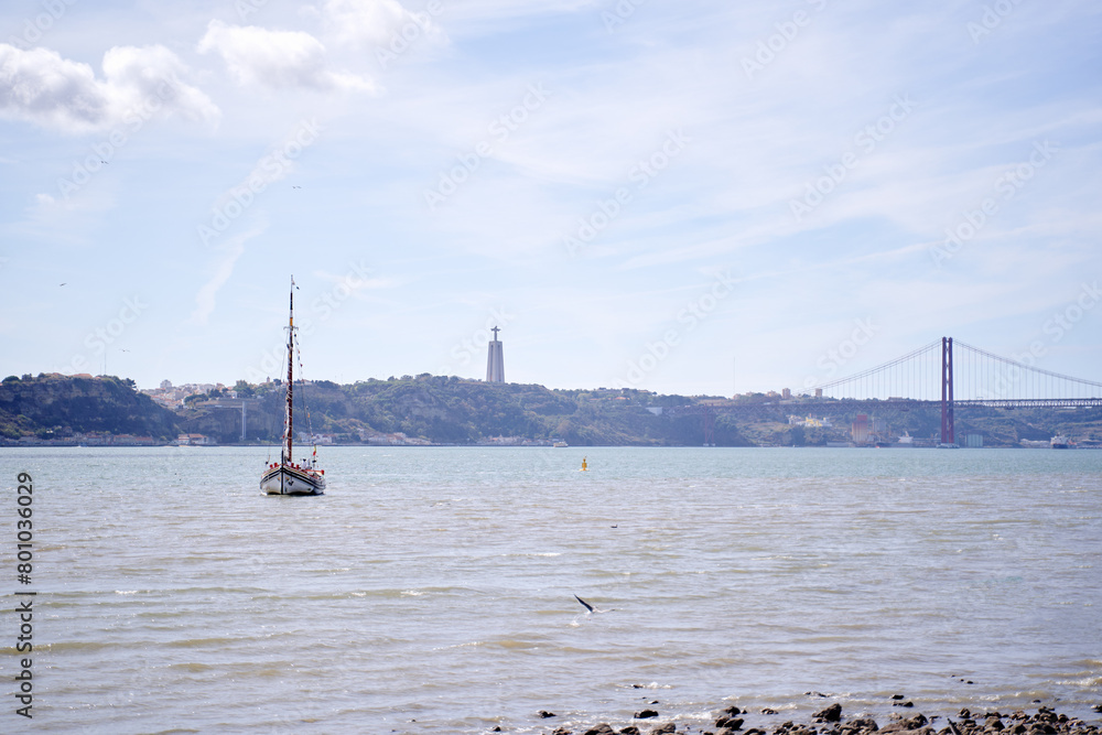 Beautiful landscape with a yacht sailing the Tejo River with the Bridge Ponte 25 de Abril view in Lisbon, Portugal Beautiful landscape with a yacht sailing the Tejo River with the Bridge Ponte 25 de Abril view in Lisbon, Portugal
