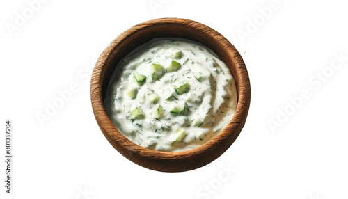 A bowl of white dip with cucumbers in it