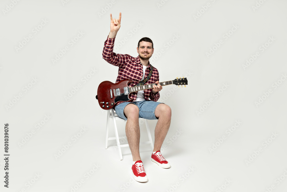 Attractive young guy playing the guitar on a white background Attractive young guy playing the guitar on a white background