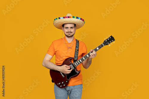 Attractive young guy playing guitar in mexican hat