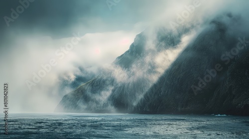 A foggy, misty day with a rocky coastline and a mountain range in the background