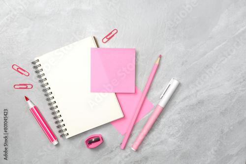 Notebook and pink sticky note and stationery on stone texture background. Work desk space
