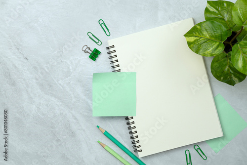 Notebook and green sticky note and stationery on stone texture background. Work desk space