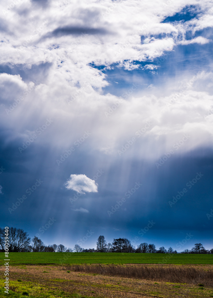 Amazing clouds. Rays of light pass through a huge cloud in the blue sky. Beneath the big cloud is a small cloud. Beautiful landscape