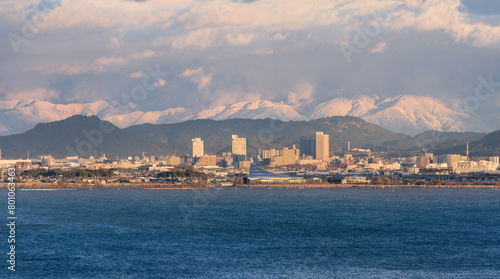 A view over Lake Biwa towards Kusatsu with snowy mountains in the background in Shiga Prefecture, Japan.