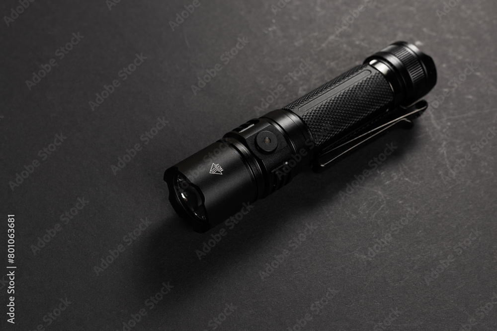 Black tactical flashlight on dark background Black tactical flashlight on dark background