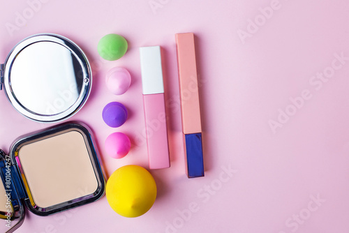Flat lay composition with cosmetics and makeup products on pink background. Colorful blender makeup sponges blending puff set and round shaped mirror	
