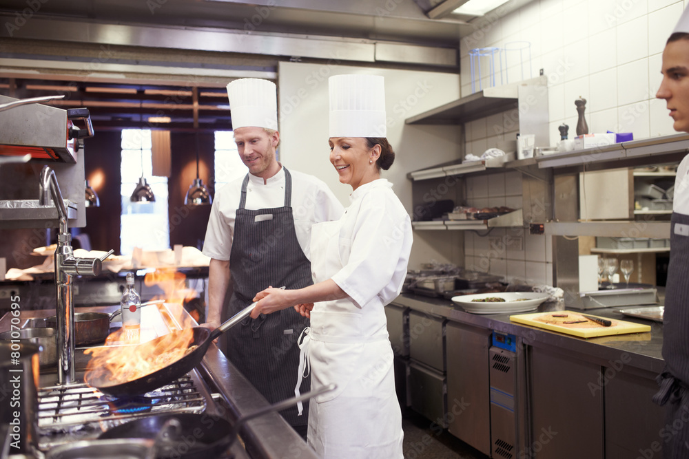 Restaurant, chef and pan with flame in kitchen for cooking, culinary career and hospitality service. Woman, hospitality and person in food industry with smile for fine dining, cuisine and preparation Restaurant, chef and pan with flame in kitchen for cooking, culinary career and hospitality service. Woman, hospitality and person in food industry with smile for fine dining, cuisine and preparation