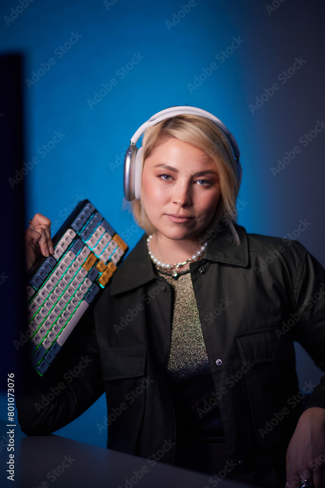 Woman with headphones at purple desk with computer monitor for entertainment Woman with headphones at purple desk with computer monitor for entertainment