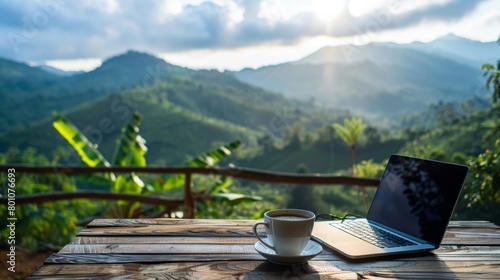 Laptop and coffee cup on wooden table with mountain view photo