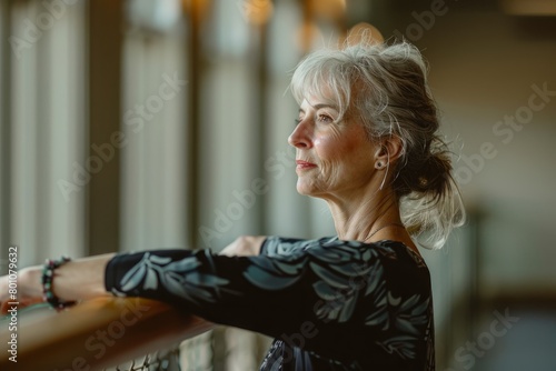 A middle-aged woman leaning on a railing, looking into the distance with a focused expression