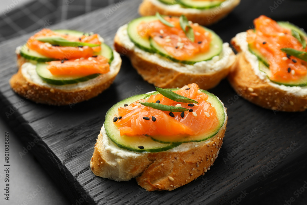 Tasty canapes with salmon, cucumber and cream cheese on grey table, closeup Tasty canapes with salmon, cucumber and cream cheese on grey table, closeup