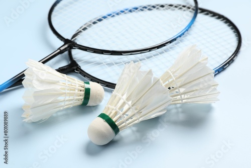 Feather badminton shuttlecocks and rackets on light blue background, closeup © New Africa