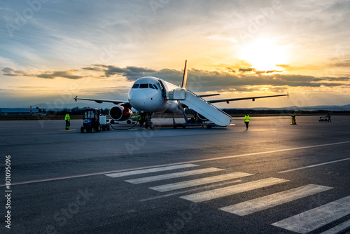Airplane at sunset - back lit. Airplane being charged and receiving cargo at the airport © Ivan