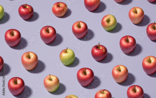 A group of red and green apples are arranged on a purple surface. 