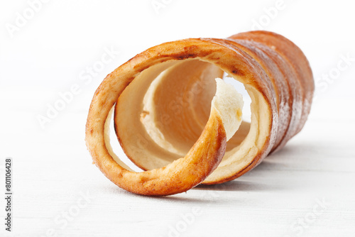 Traditional Hungarian donuts (Kürtöskalács), commonly known as chimney cake, on a white wooden background from the front view, with selective focus.