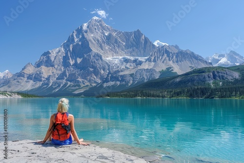 Woman Sitting on Rock, Looking at Mountain Lake