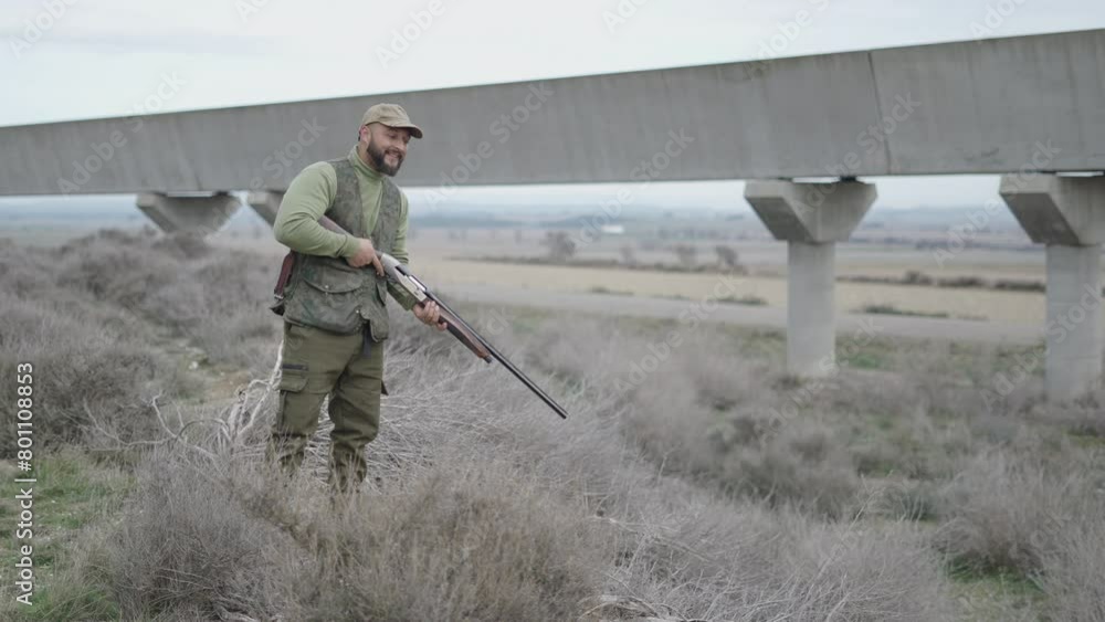 A hunter with a rifle observing something A hunter with a rifle observing something