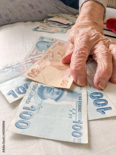 wrinkled hand of senior old person with money, turkish lira banknotes photo