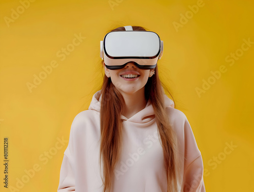 Portrait of happy young ginger haired woman wearing white augmented virtual reality glasses on yellow color studio background with copy space