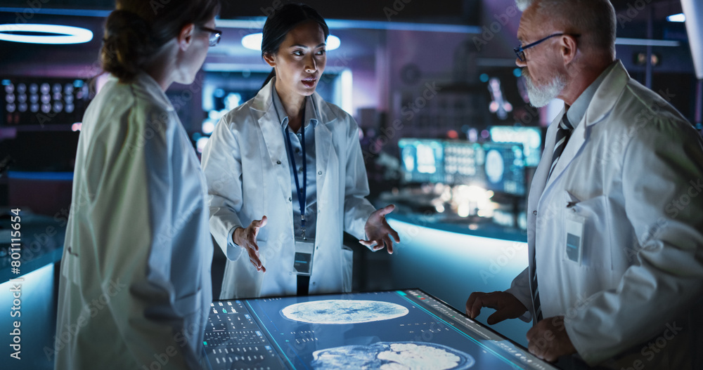 Fototapeta premium Modern Hospital Medical Research Center: Diverse Colleagues Gathered Around Interactive Touch Screen Table With MRI Scans Of Brain On Display. Doctors Discussing Rehabilitation Solutions After Stroke.