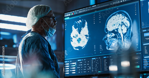 Quadro su tela Medical Hospital Research Laboratory: Caucasian Male Neurosurgeon Looking At TV Screen With Brain MRI Scans Of Patient, Analyzing, Preparing For Complicated Neurosurgery, Wearing Surgical Gown