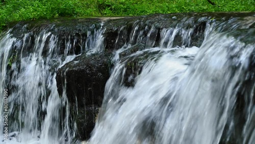 Streams of cold water flowing from a stone waterfall in a wild forest valley.