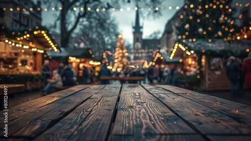 Festive Christmas market ambiance with twinkling lights and a rustic wooden foreground in focus. © tashechka